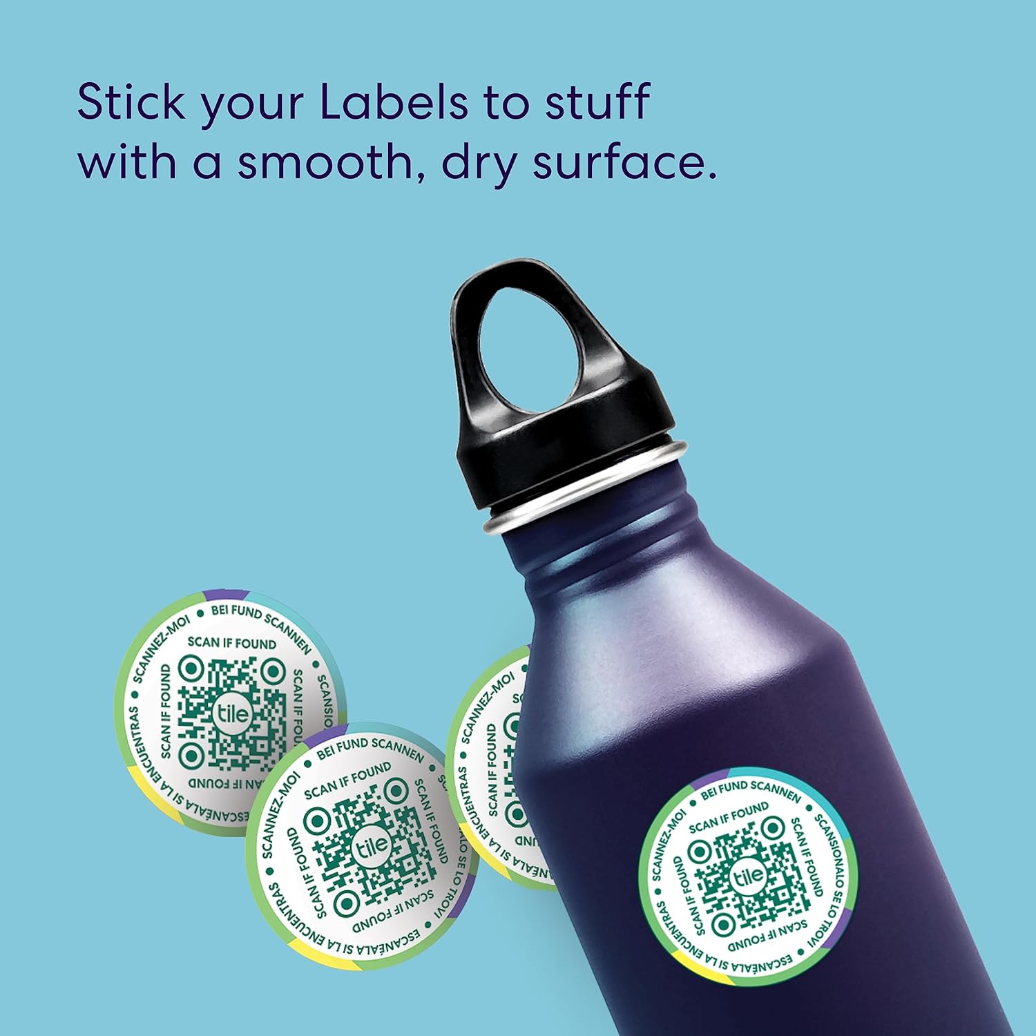 This image contains a dark blue water bottle with a black cap lying diagonally on a light blue background. There are also circular green and TileMate white labels with QR codes next to the bottle.