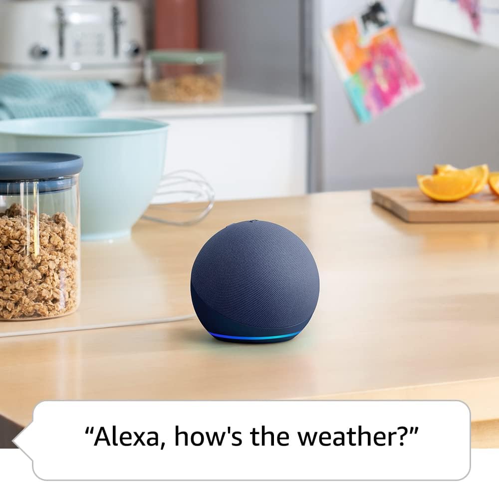 The image depicts a modern kitchen counter with various items on it. In the foreground, there's a fourth-generation Amazon Echo Dot 5 smart speaker, recognized by its spherical design and the signature blue light indicating that it’s active, possibly responding to the voice command shown in the speech bubble.