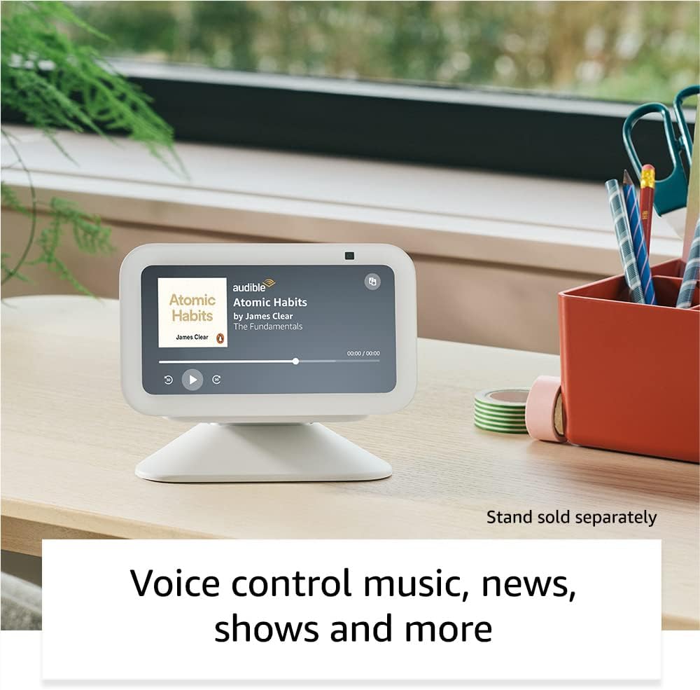 The image shows an Echo Show 5 placed on a wooden table. The display screen is indicating that it is playing an audiobook.