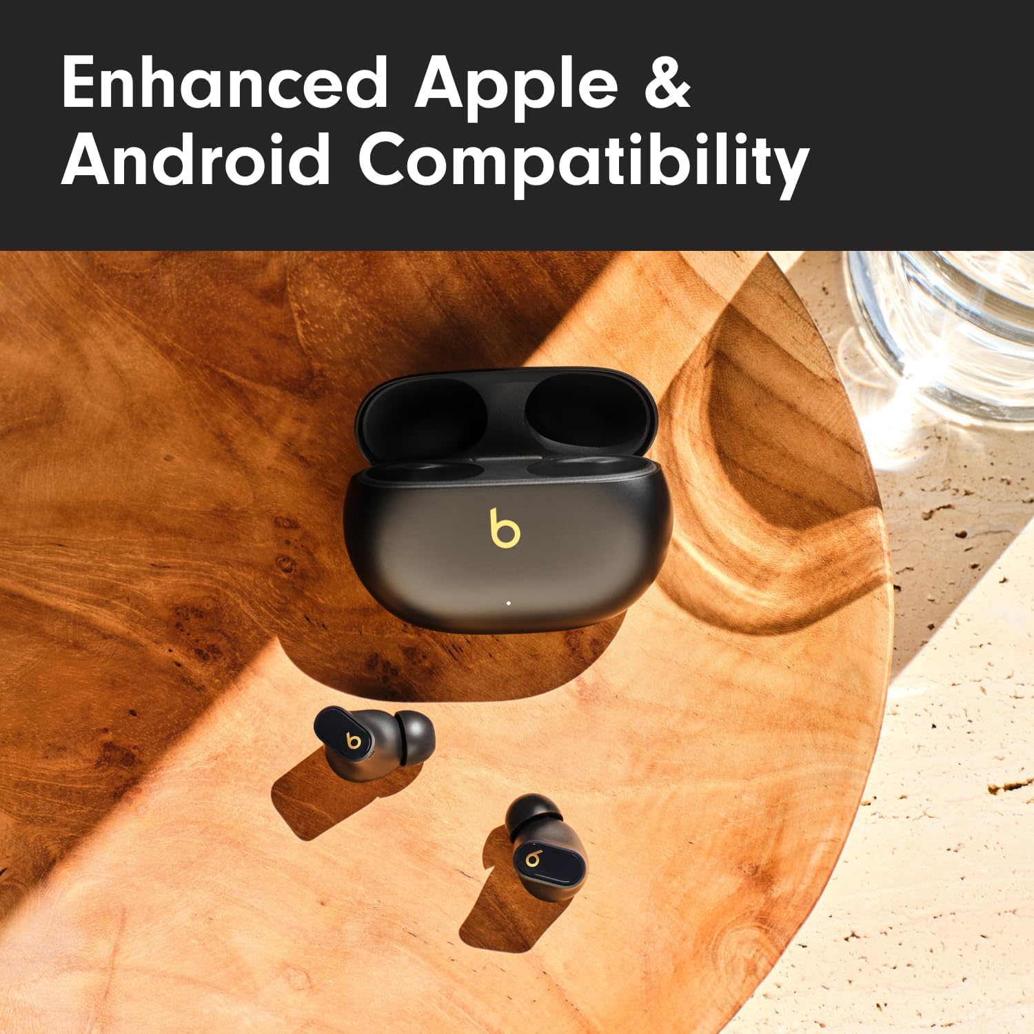 This is an image of a pair of Beats Studio Buds Plus earbuds with their charging case. The earbuds and the case have a prominent 'b' logo, which is indicative of the brand Beats by Dr. Dre.