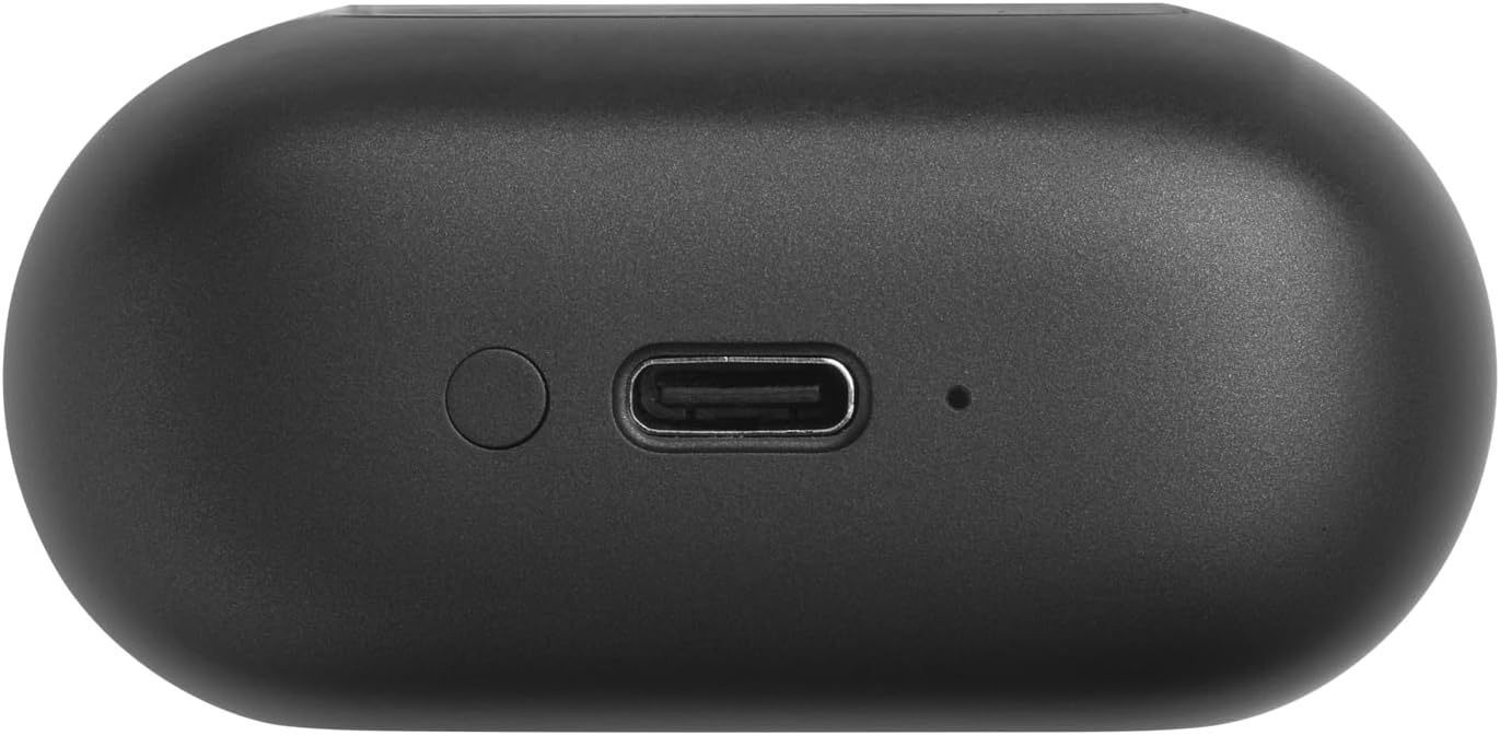 The image shows a black, oval-shaped object with a USB-C port in the center, a button to the left of the port, and a small indicator light or hole to the right of the port. Based on these features, this appears to be a charging case for JBL Tour Pro 2 earbuds. The USB-C port is used for charging the case, and, in turn, the case charges the earbuds when they are stored inside. The button might be used to check the battery status or to initiate pairing with a Bluetooth device, and the small hole or light is likely an LED indicator for charging status or battery life.