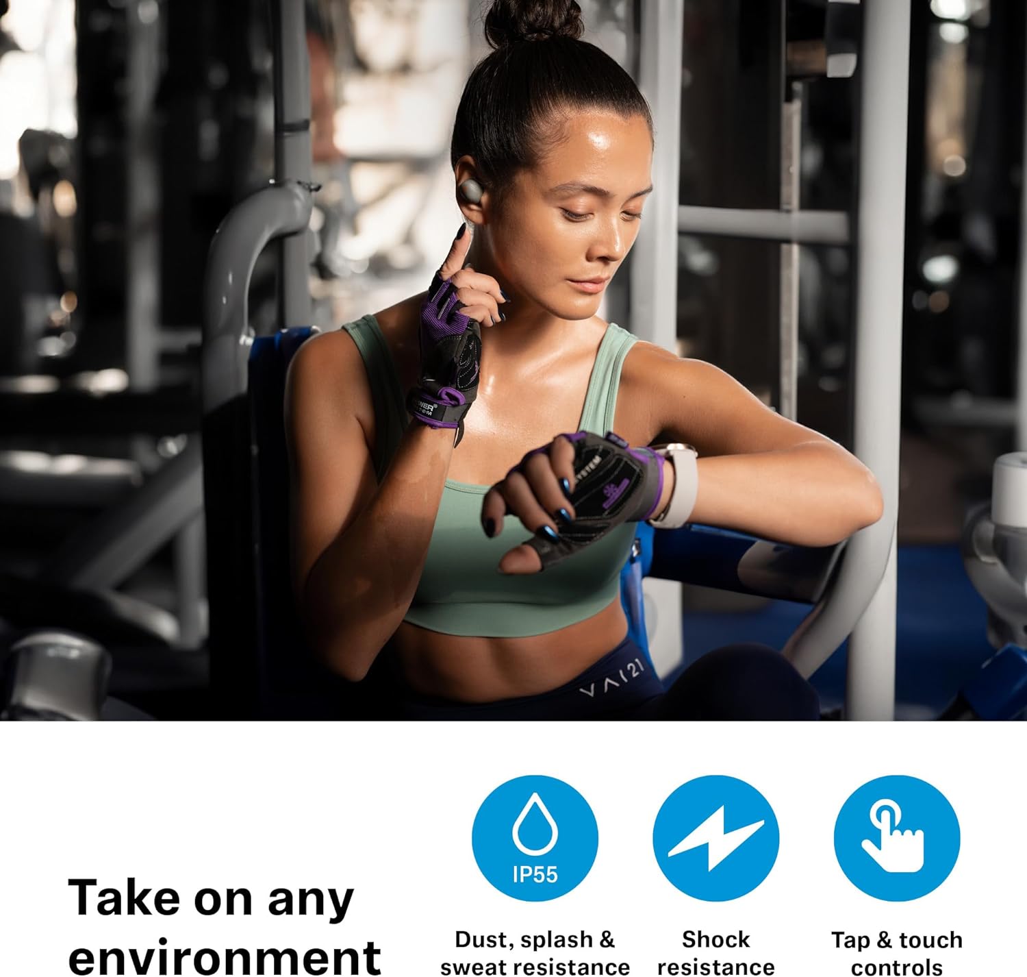 The image shows a woman sitting on gym equipment, likely between exercises. She is dressed in workout attire—a sports bra and leggings—and is wearing fitness gloves. She appears to be adjusting Sennheiser Momentum Sport Earbuds. The lighting suggests an indoor gym environment.